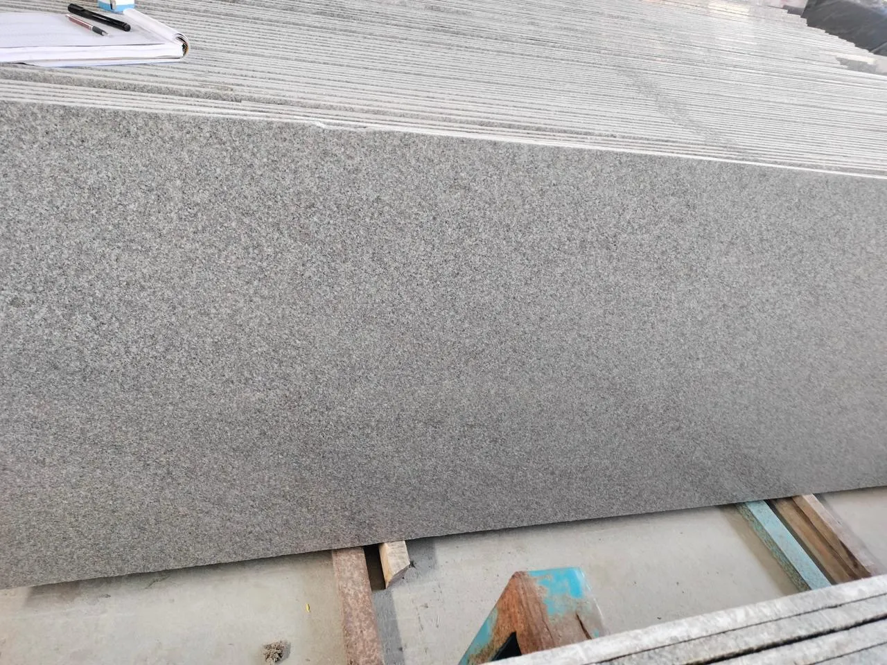 A bundle of grey granite slabs in the yard with an order book on top